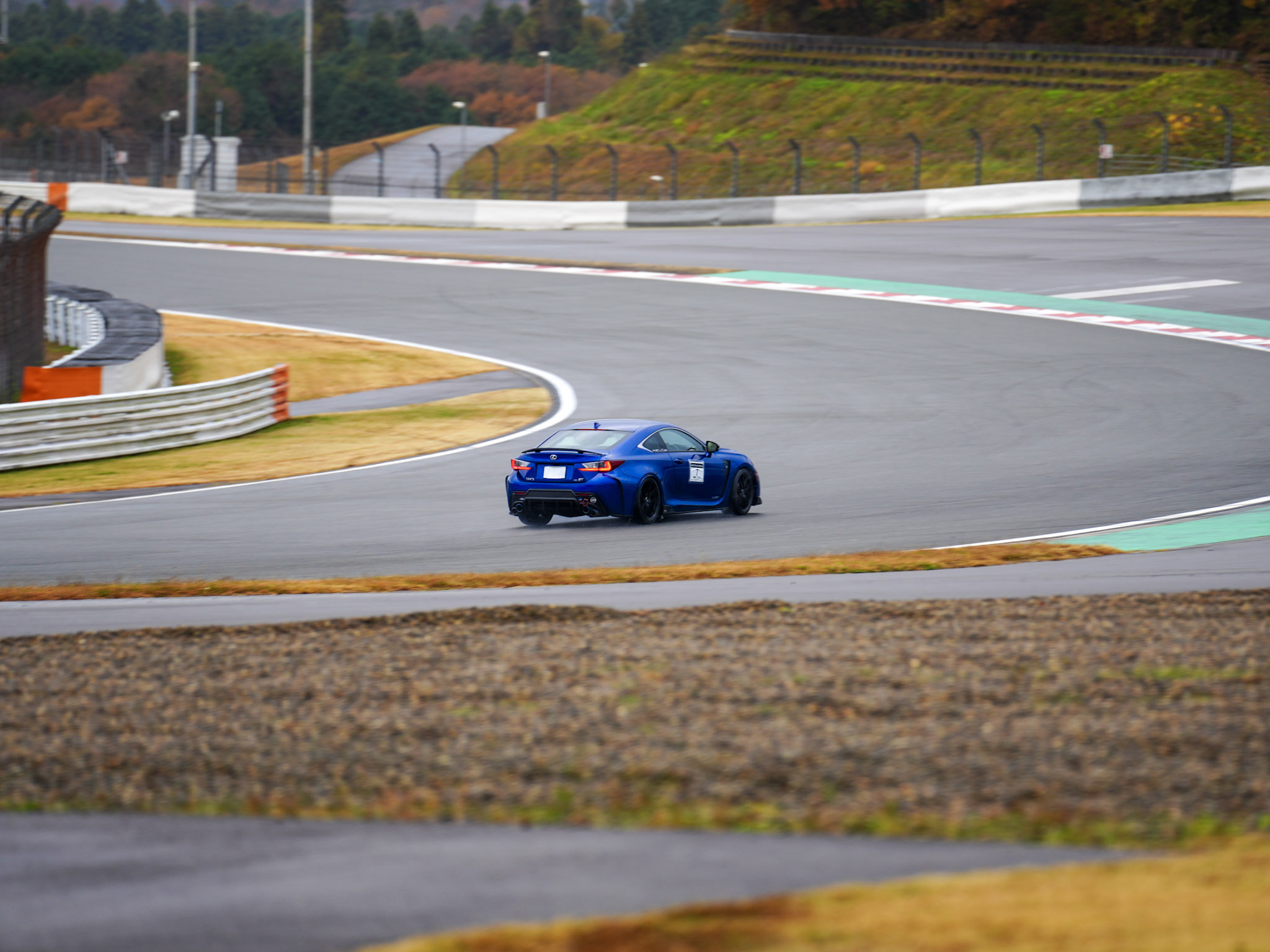 Blue Lexus RC-F cornering at Fuji Speedway with autumn foliage in the background