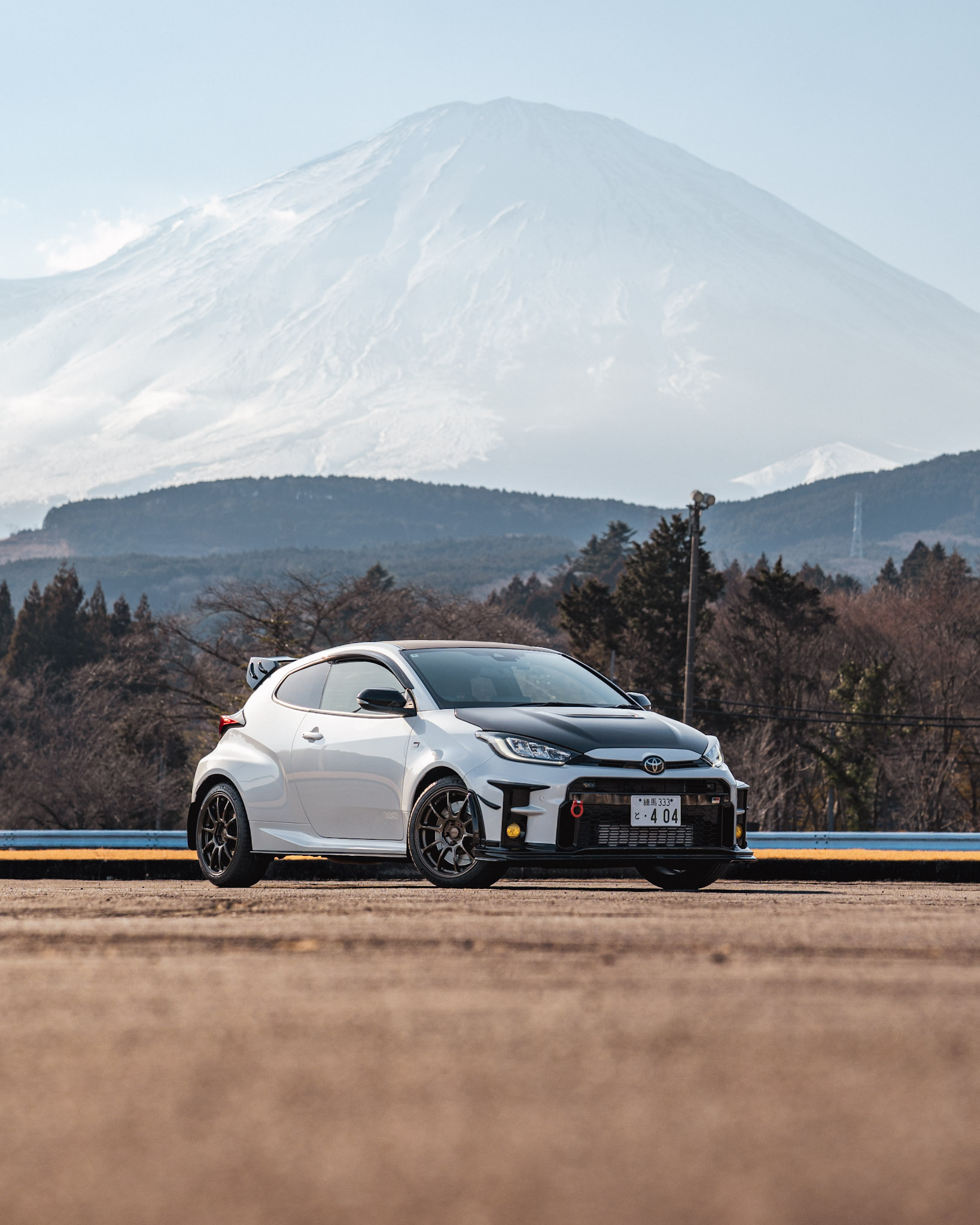 White Toyota GR Yaris parked against a snow-capped Mt. Fuji backdrop